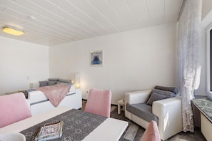 Une chambre moderne avec un lit, deux canapés, une petite table et une fenêtre avec des rideaux.
