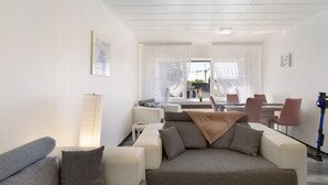 Una sala de estar moderna con un sofá, una mesa de centro y un comedor con sillas y una mesa.