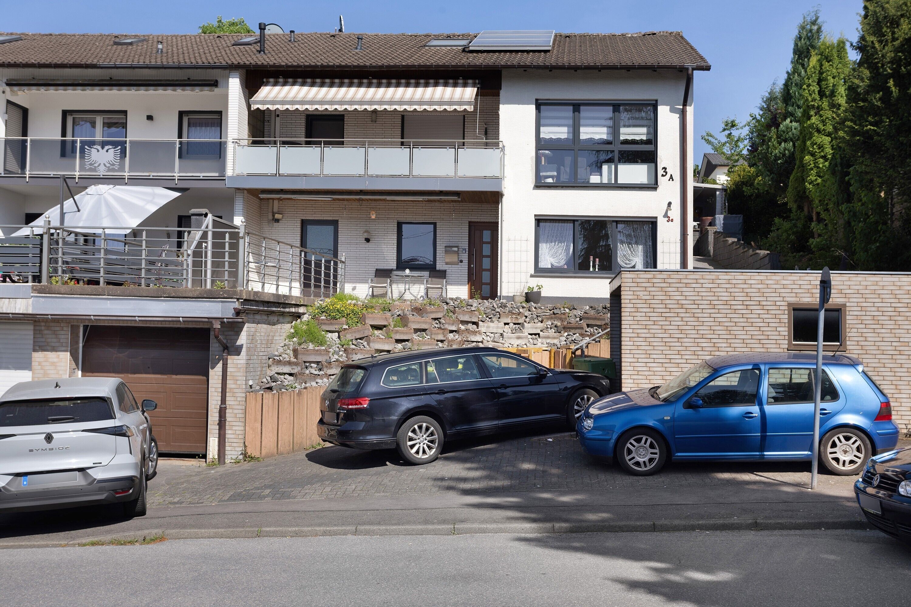 A two-story residential building with a garage, a balcony, and a parked car.