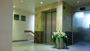 A lobby with a reception desk, an elevator, and a decorative plant arrangement. - Apartment 'Dargies' with Sea View, Balcony and Wi-Fi (Cuxhaven)