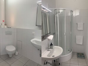 Un baño moderno con inodoro, lavabo y ducha con mampara de vidrio.