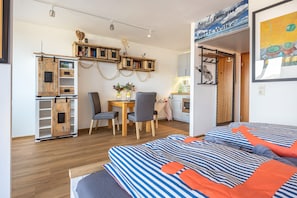 A room with a bed, a desk, a chair, and a kitchenette.