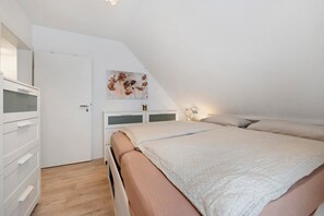 A bedroom with a bed, a dresser, a door, and a wall-mounted artwork.