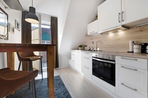 A modern kitchen with white cabinets, a black oven, and a wooden countertop.