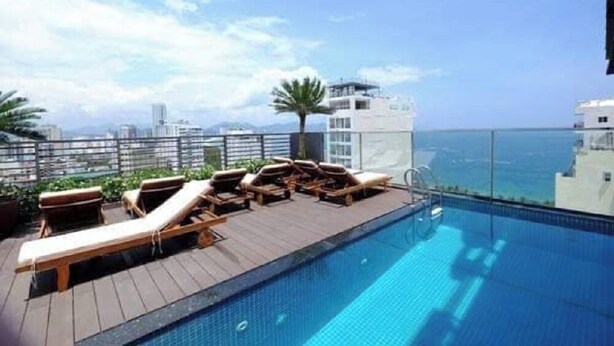 Una piscina en la azotea con sillones de descanso y vista al mar.