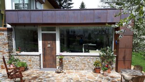Una casa moderna con un patio de piedra, una puerta de madera y plantas en macetas.