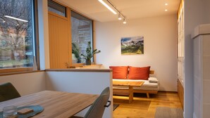 Un interior moderno con una mesa de comedor, un sofá, un ventanal con vistas y un cuadro en la pared.