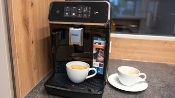 Een koffieapparaat met een kop koffie op een dienblad, een tweede kop op een schoteltje, en een houder voor koffiecups.