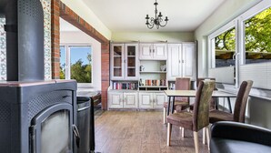 A kitchen with a large stove, white cabinets, a dining table with chairs, and a window with blinds.