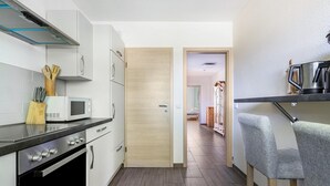 A modern kitchen with a microwave, stove, and wooden utensils on the counter.