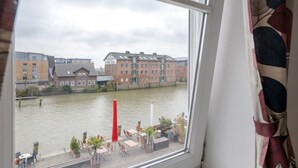 A view of a river with buildings across it, a red pillar, and outdoor seating by the water. - Apartment 'Hafenambiente' with Private Terrace and Wi-Fi (Husum)