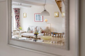 A living room with a sofa, a dining table, and a lamp.