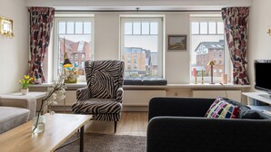 A living room with a zebra-patterned armchair, a sofa, a coffee table, and a TV. - Apartment 'Hafenambiente' with Private Terrace and Wi-Fi (Husum)