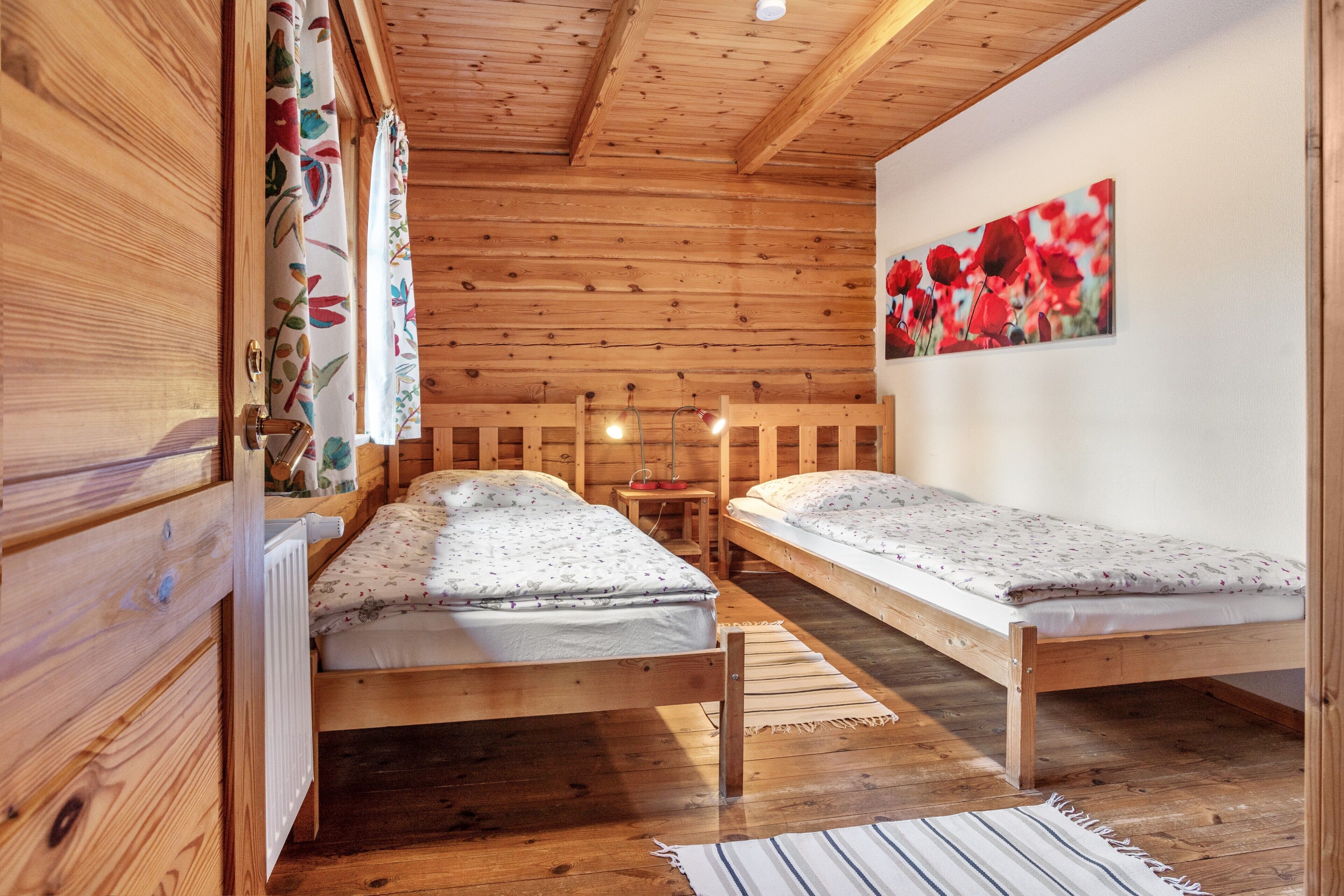 Une cabane en bois avec deux lits simples, une petite table et un tableau accroché au mur.