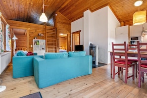 A wooden interior with a sofa, chairs, a TV, and a kitchen area.
