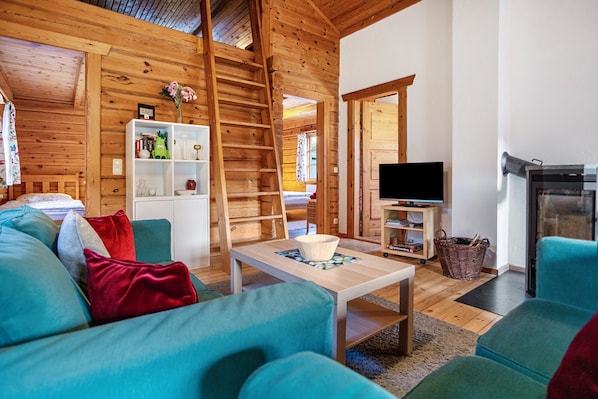A wooden interior with a sofa, a television, and a fireplace.