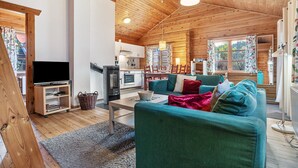 A cozy cabin interior with a wooden ceiling, a television, a sofa, a dining table, and a kitchen area. - Apartment 'Johanna' with Private Terrace, Private Garden and Wi-Fi (Zislow)