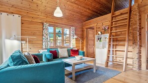 A cozy cabin interior with a sofa, coffee table, and a ladder against a wooden wall. - Apartment 'Johanna' with Private Terrace, Private Garden and Wi-Fi (Zislow)