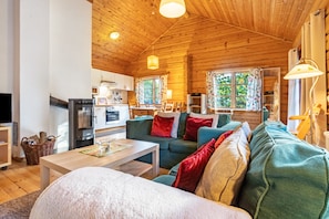 L’intérieur chaleureux d’un chalet avec un plafond en bois, un canapé, une table et un coin cuisine.