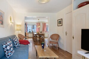 A living room with a sofa, chairs, a dining table, and a TV.