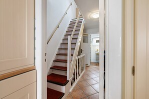 A staircase leading to a landing with a kitchen area in the background.