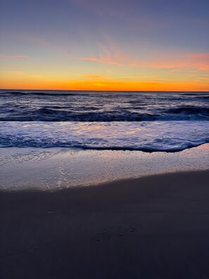 Une plage avec des vagues et un coucher de soleil.