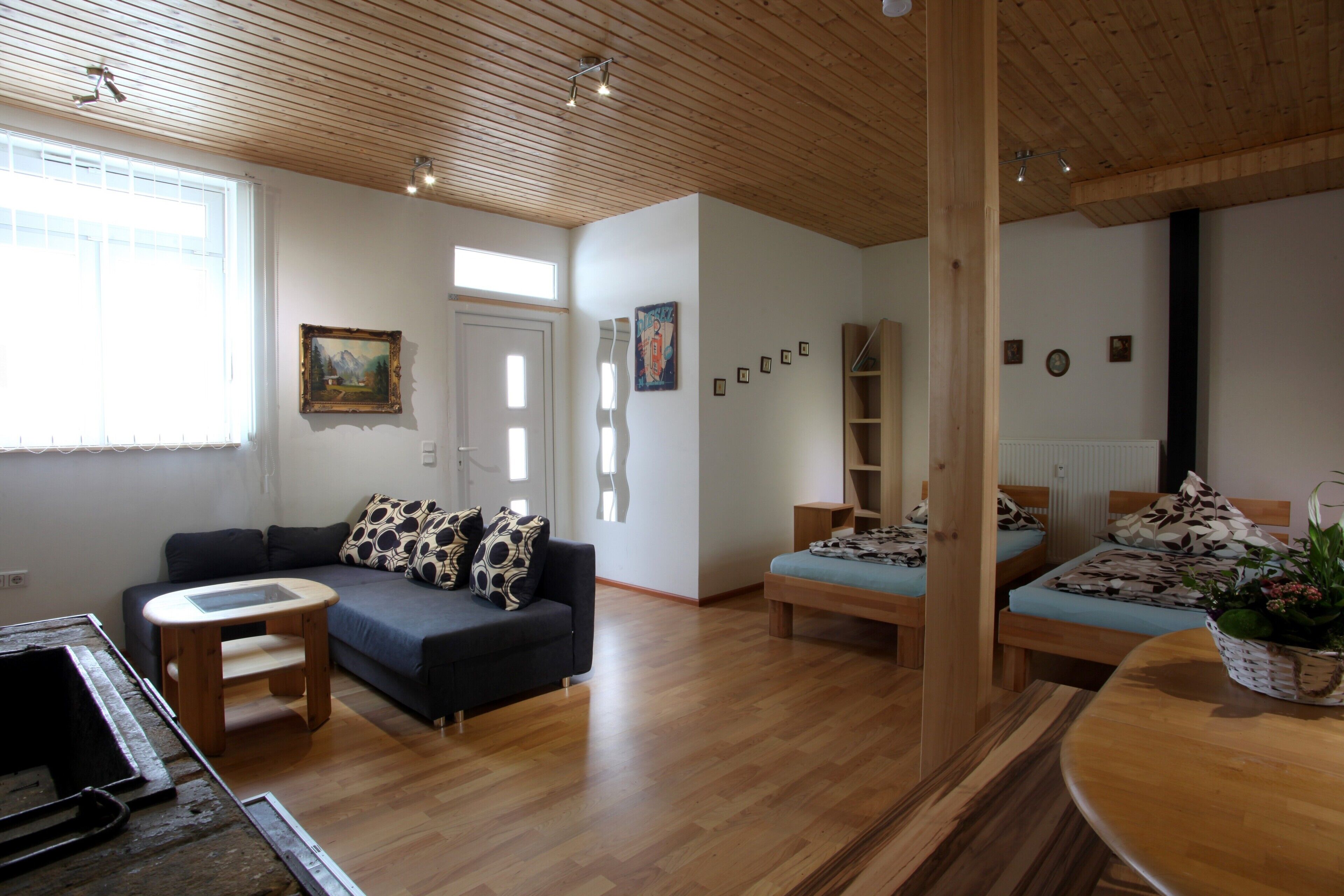 Un salon moderne avec un canapé, une petite table, un plancher en bois et un plafond avec des poutres en bois.