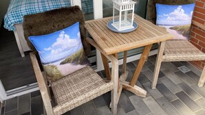 A balcony with wicker chairs, a small table, and a view of the outdoors. - Apartment 'Jan, 35qm' with Balcony (Horumersiel-Schillig)