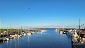 A marina with boats docked along the waterway, a clear sky, and a distant view of the horizon. - Apartment 'Jan, 35qm' with Balcony (Horumersiel-Schillig)
