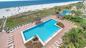 Een resort met een zwembad, ligbedden en uitzicht op het strand.