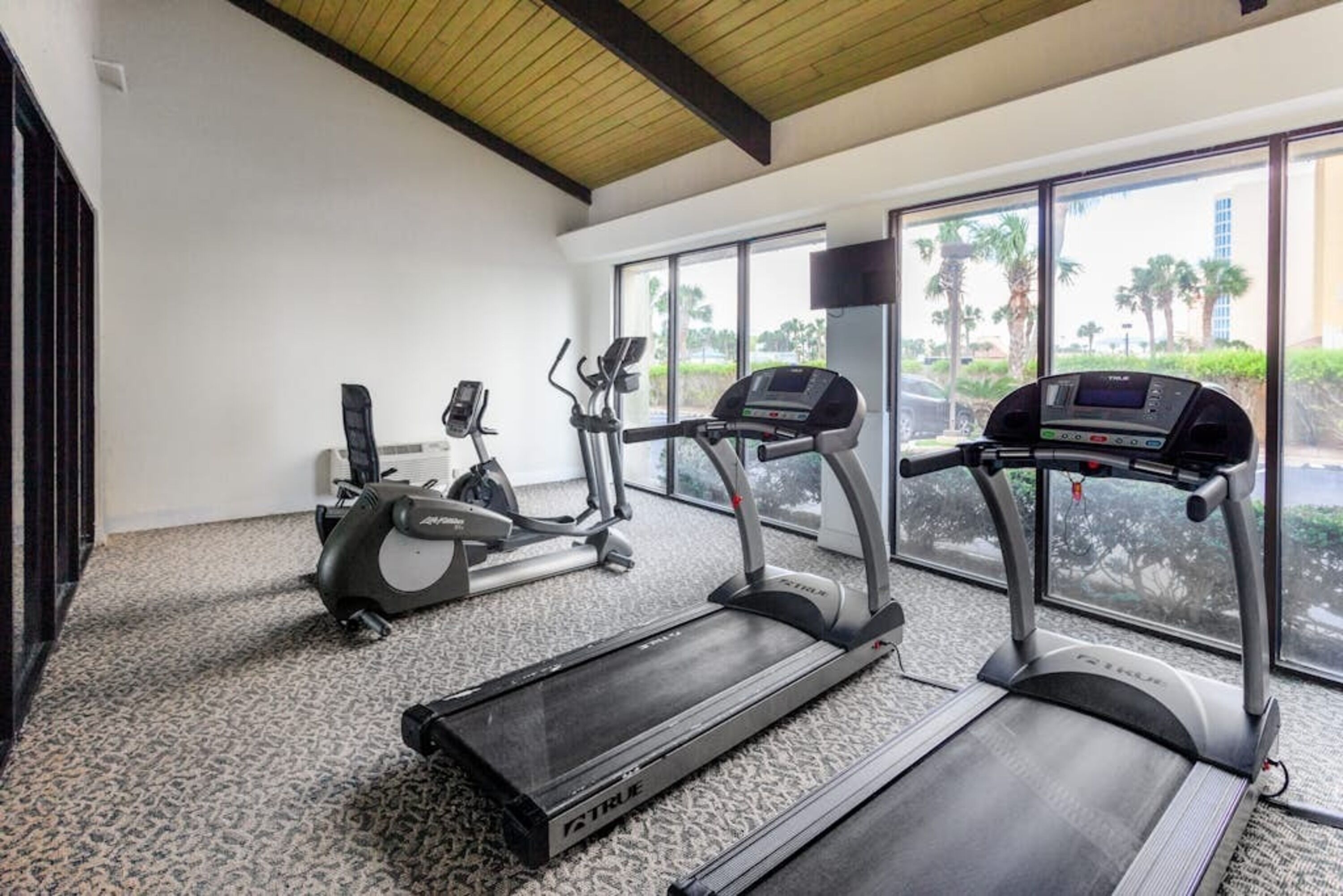 Ein Fitnessraum mit Laufbändern, Crosstrainern und einem Ergometer.