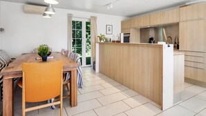 A modern kitchen with wooden cabinets, a central island, and pendant lighting.