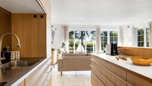 A modern kitchen with a central island, a built-in sink, and a view of a garden through large windows.