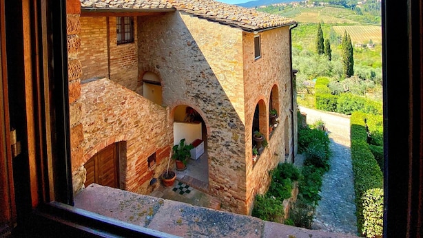 A rustic stone building with a tiled roof, arched windows, and a courtyard with potted plants. - Montagnana Country House - Relax and stunning view (San Gimignano)