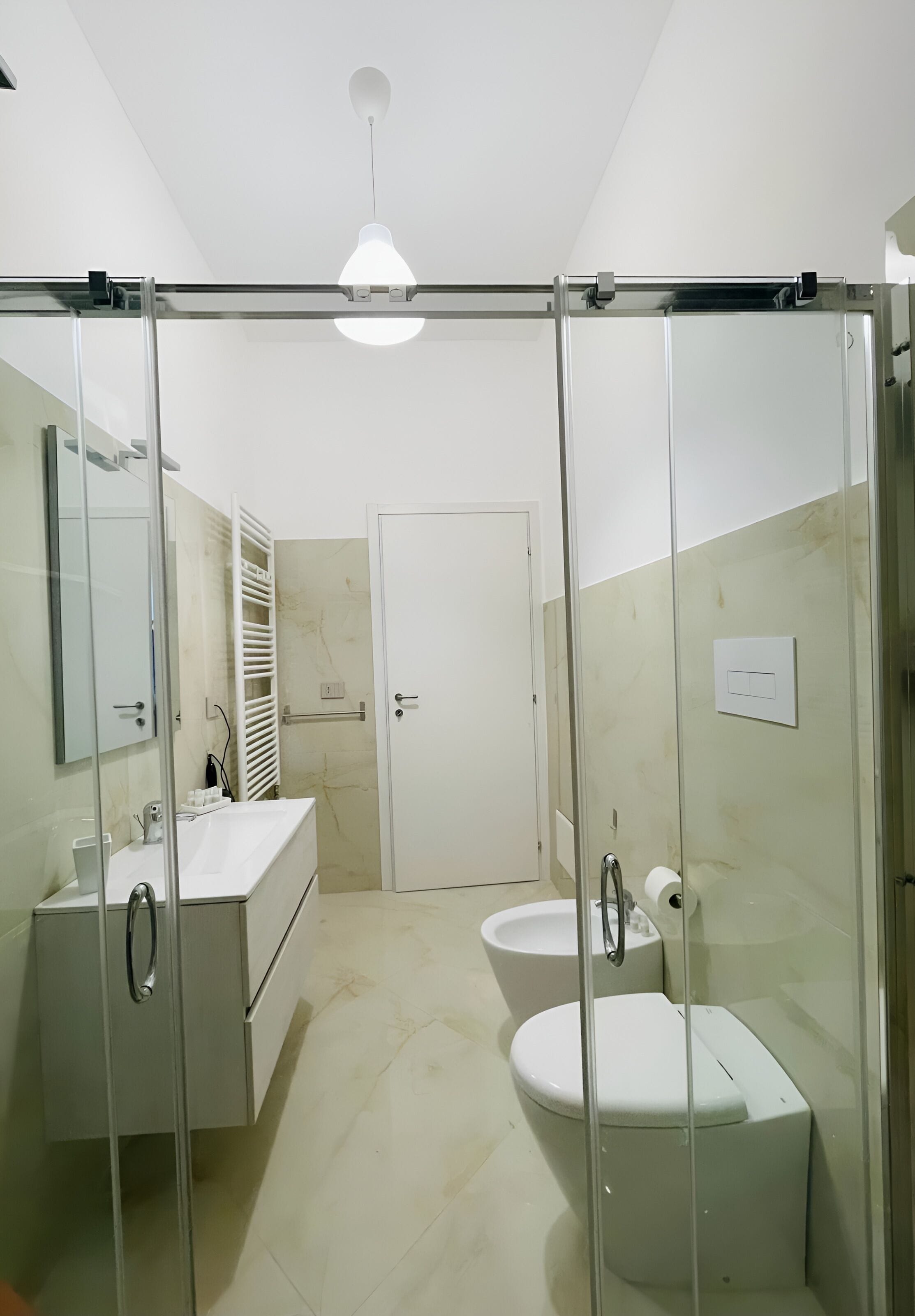Ein modernes Badezimmer mit Duschkabine aus Glas, einem weißen Waschbecken und einer Toilette.