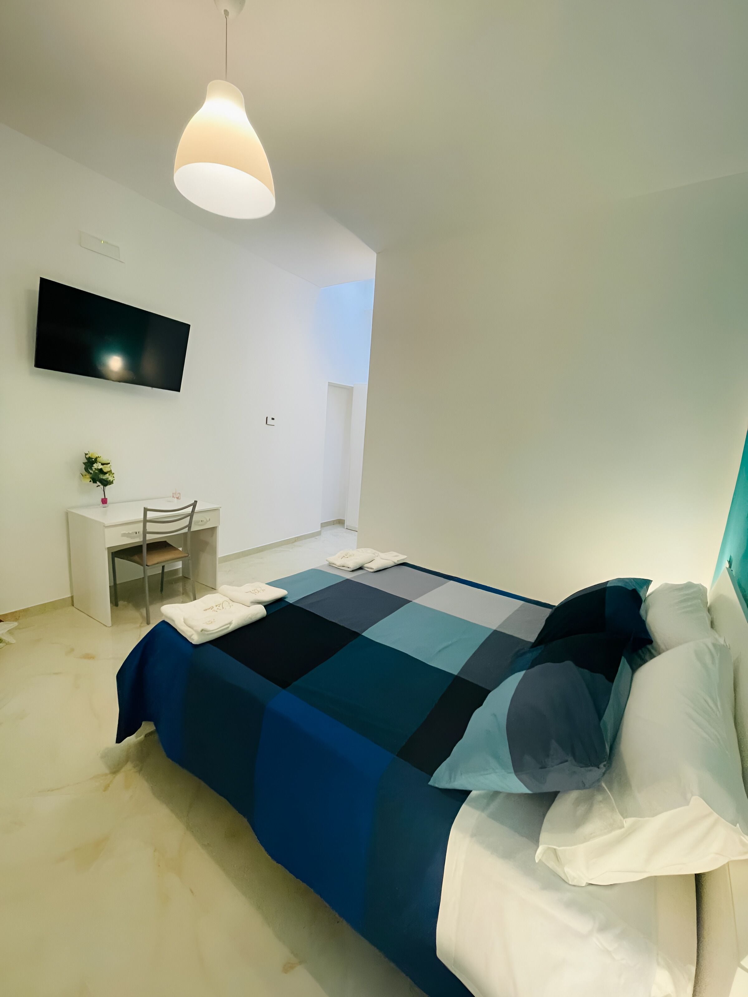 Un dormitorio moderno con cama, escritorio y televisor.