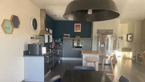 Eine moderne Küche mit einer zentralen Kochinsel, dunkelblauen Wänden und einer großen Pendelleuchte.