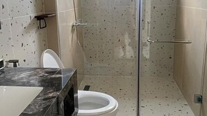Un baño moderno con ducha de vidrio, inodoro blanco y encimera de mármol.