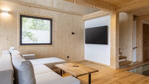 Un salon moderne avec un plancher en bois, un canapé, une table basse et un téléviseur fixé au mur.