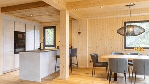 Une cuisine moderne dotée d’un îlot central, de tabourets de bar et d’un coin repas avec une table et des chaises en bois.