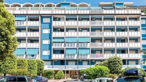 A multi-story hotel with balconies, air conditioning units, and a parking area in front. - Apartment in Caorle with balcony (Caorle (VE))