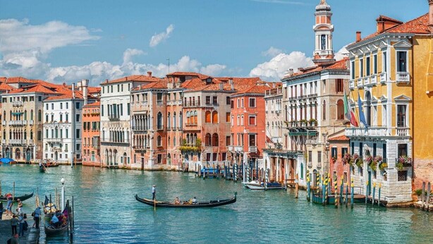 A canal with buildings along the water's edge, gondolas, and a clear blue sky. - Apartment in Caorle with balcony (Caorle (VE))