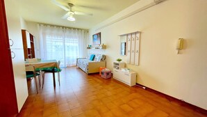 A room with a dining table, chairs, a bed, a small cabinet, and a ceiling fan. - Apartment in Caorle with balcony (Caorle (VE))