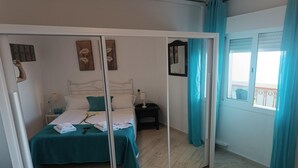 A bedroom with a bed, a nightstand, a mirror, and a window with curtains. - Apartment with terrace and sea views (Benalmádena)