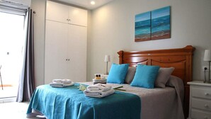 A bedroom with a bed, a nightstand, a wardrobe, and a painting on the wall. - Apartment with beach and garden views (Benalmádena)
