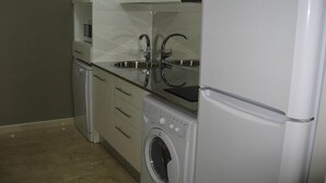 Cocina compacta con lavadora, refrigerador y microondas.