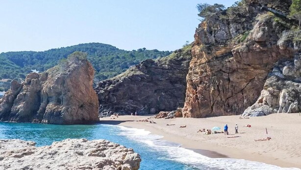 Ein Strand mit Felsformationen und blauem Himmel.