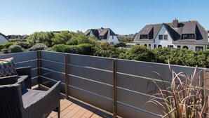 A rooftop terrace with wicker furniture and a view of neighboring houses.