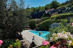 Une piscine entourée d’une végétation luxuriante et d’un mur de pierre.