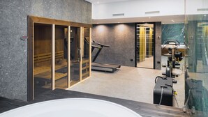 A modern hotel lobby with a treadmill, a glass elevator, and a sauna area.